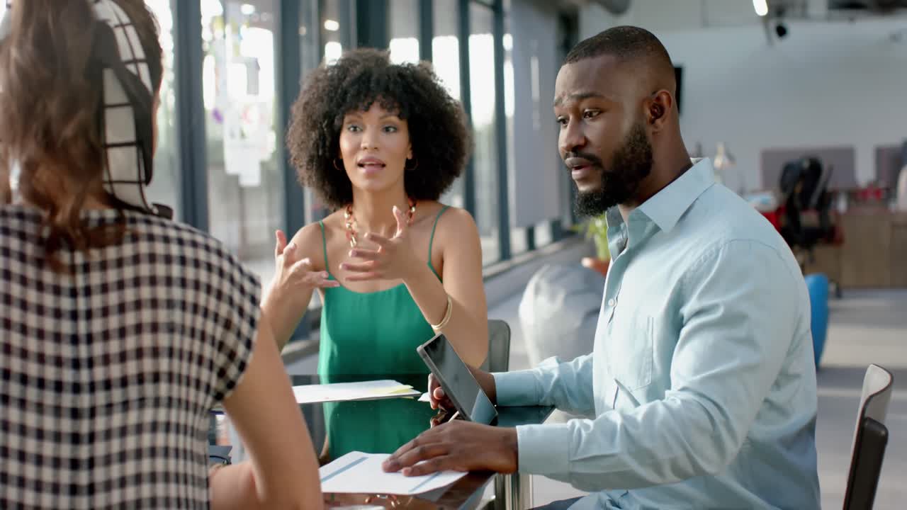 African american businessman discussing with team of colleagues at office