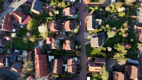 red bicycle lane between residential area at sunset time. aerial top down flyover shot. solar panels in german town. two-story single family homes with red tile in american neighborhood.
