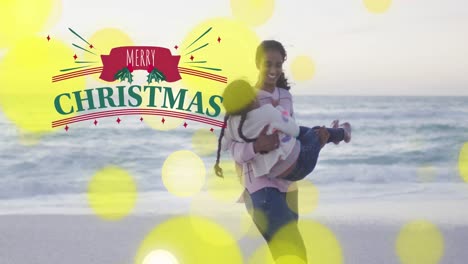 Animación-De-Texto-De-Feliz-Navidad-Con-Puntos-De-Luz-Sobre-Una-Mujer-Birracial-Y-Su-Hija-En-La-Playa