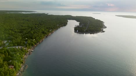 aerial view of a forested coastline with a lighthouse and bay