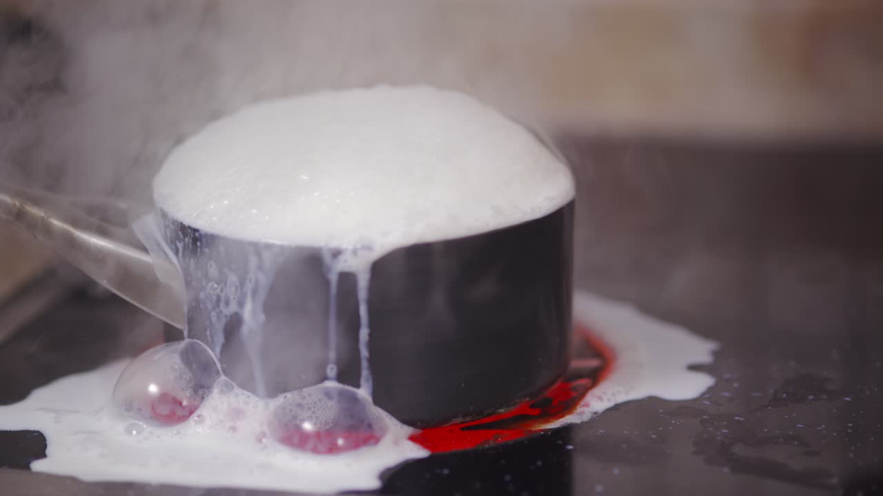 스토브 위의 우유 비가 여서 증기가 빠져나와 우유 거품이 오븐 꼭대기에 붙어 있습니다.