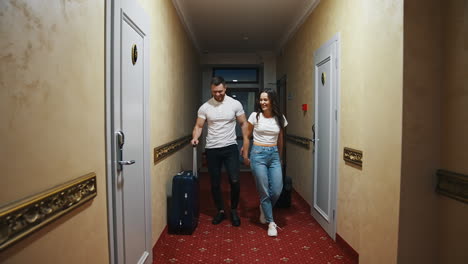 young couple in the corridor of a hotel. beautiful woman and man with suitcases leaving hotel. happy couple returning from family vacation.