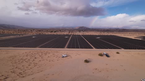 Aerial-Drone-Footage-of-Solar-Panel-Field-in-Joshua-Tree-National-Park-on-a-Sunny-Day-with-rainbow-in-the-background,-wide-shot-pan