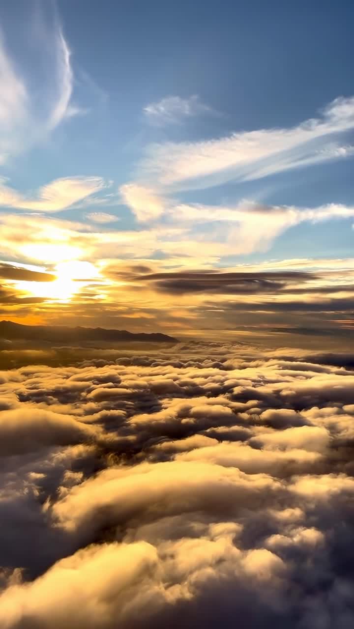 Video aereo riprende un tramonto mozzafiato su nuvole soffici, mostrando un cielo sereno e dorato.