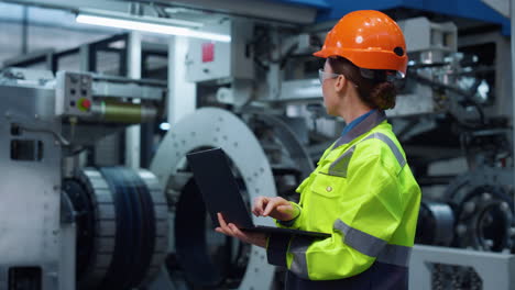 Uniformed-specialist-working-laptop-computer-on-modern-huge-digital-factory.