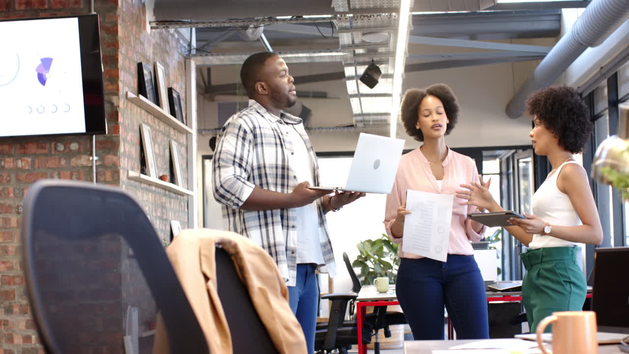 African American man and two women discussing work in modern office