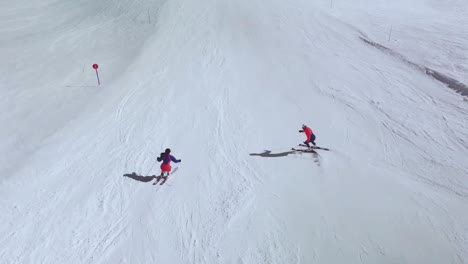 drone view of skiers going down a slope in the pyrenees, spain, learning to ski