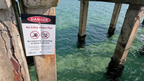 danger sign under pier, clear water visible