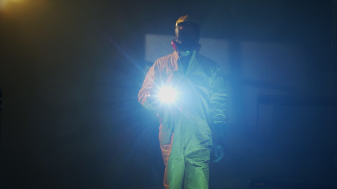hombre vestido con traje hazmat explora una habitación oscura