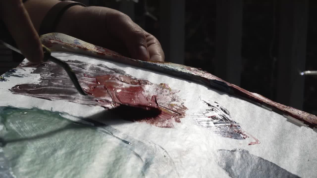 여성 예술가 는 해가 지는 동안 밖 의 팔레트 에 은 페인트 를 어 기 위해 팔레트 칼 을 사용 한다