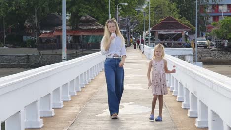 mother and daughter walking on a pier