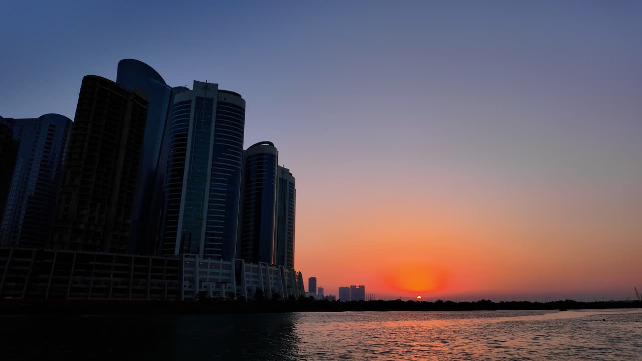 Sunset with the sun just on the horizon as seen from Al Reem Island looking towards Abu Dhabi, United Arab Emirates
