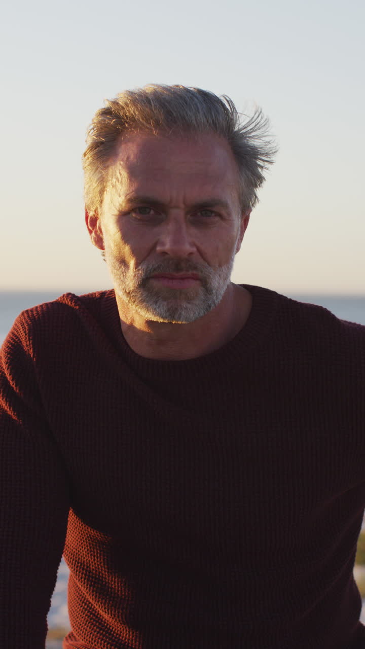 retrato de video vertical de un hombre caucásico sonriente en la playa, disfrutando del tiempo libre