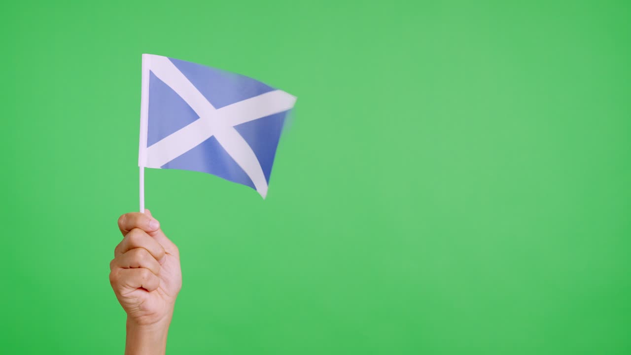En hånd, der holder et skotsk flag, som blafrer i vinden
