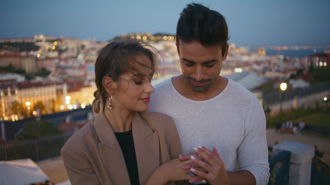 Affectionate sweethearts touching hands embracing at night city lights closeup.