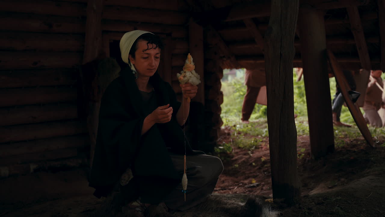 Woman Spinning Wool in a Wooden Cabin
