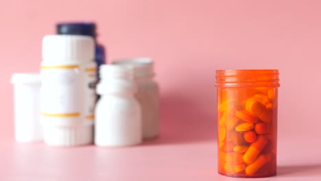 primer plano de una botella de pastillas naranja con varios medicamentos en el fondo