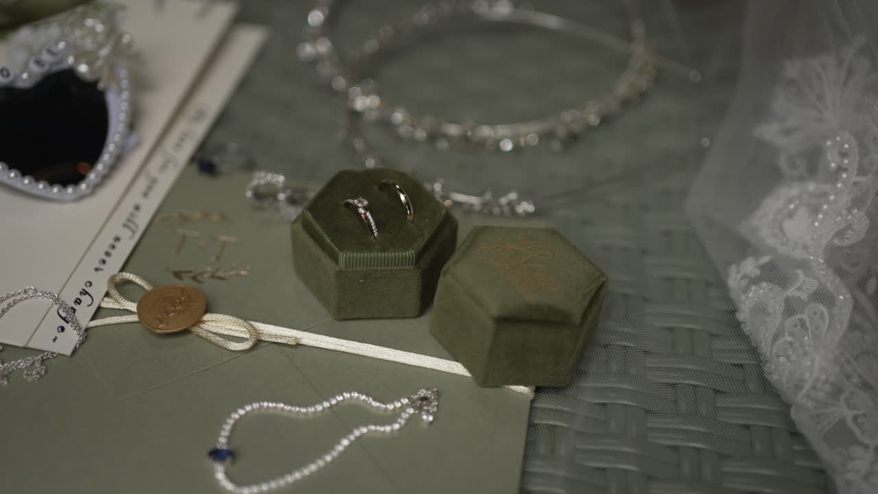 Close up of wedding rings in velvet box surrounded by pearl and crystal accessories