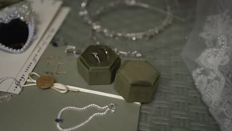 close up of wedding rings in velvet box surrounded by pearl and crystal accessories