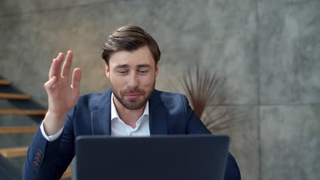 hombre de negocios sonriente hablando en línea en la cámara de la computadora portátil en la oficina