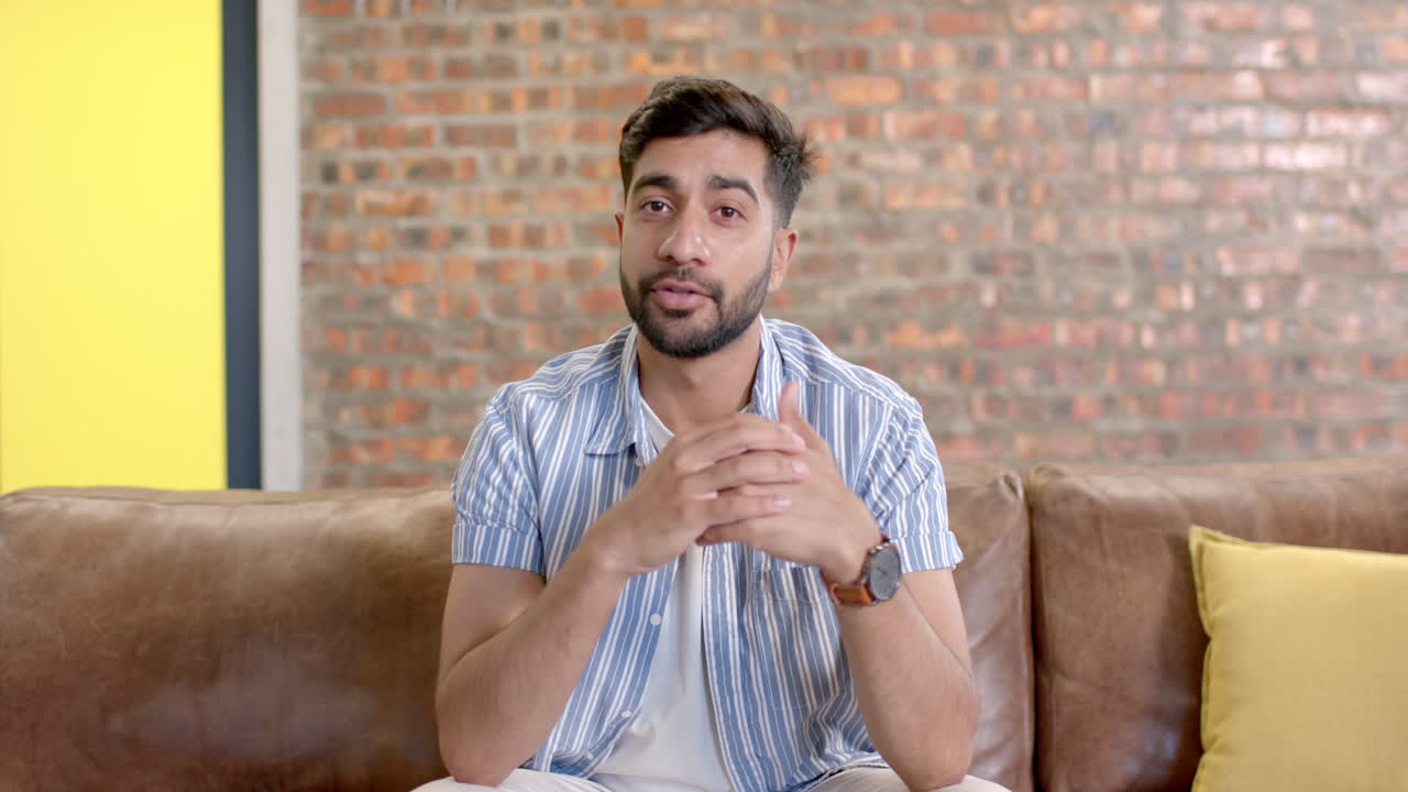 Man sitting on couch, explaining something with hands in modern office setting