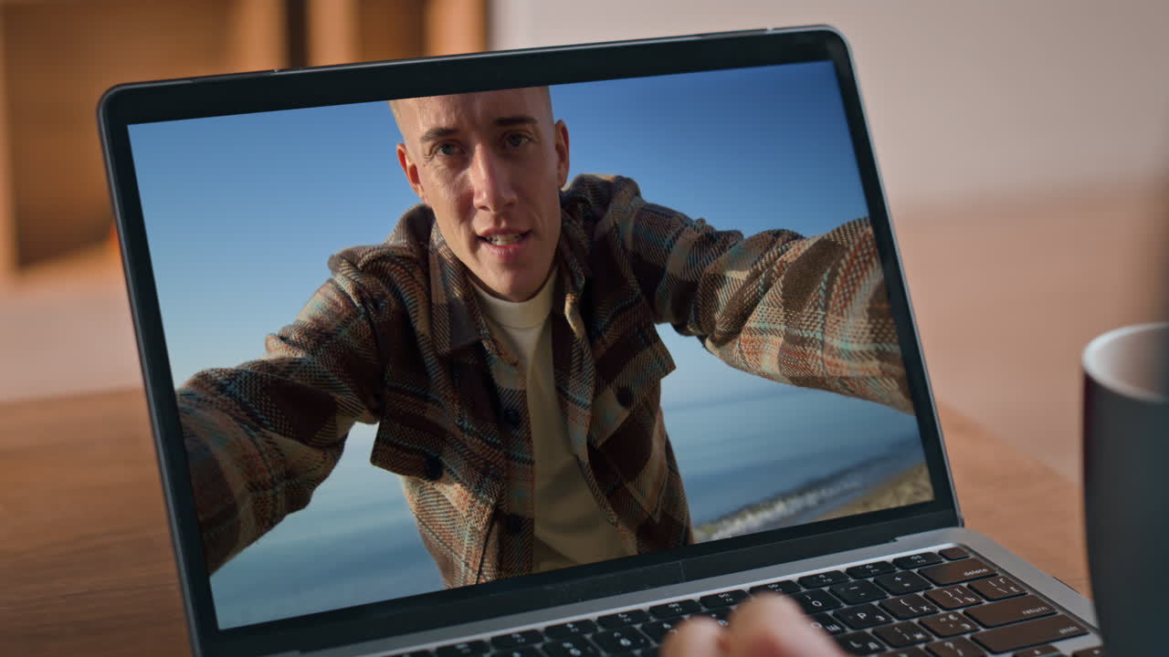 Man on video call at the beach on a laptop