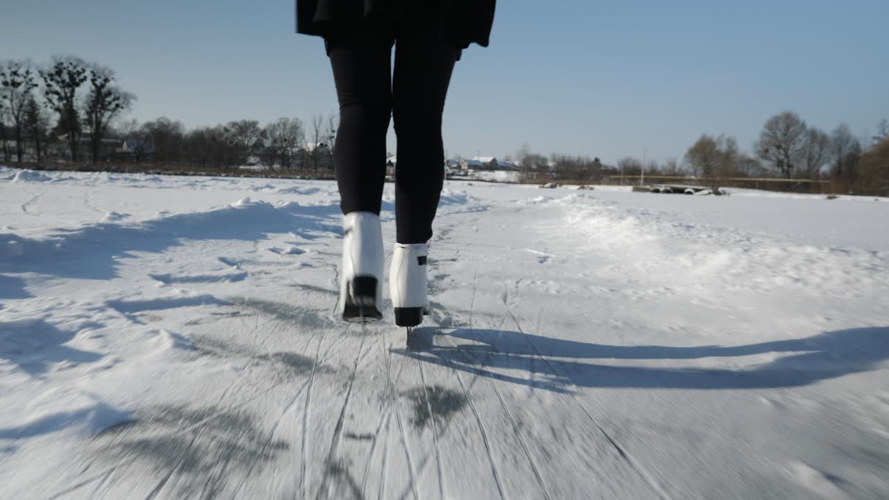 스커트와 색 피겨 스케이트를 입은 여성은 얼어붙은 호수에서 아이스 스케이팅을 하고 있습니다.