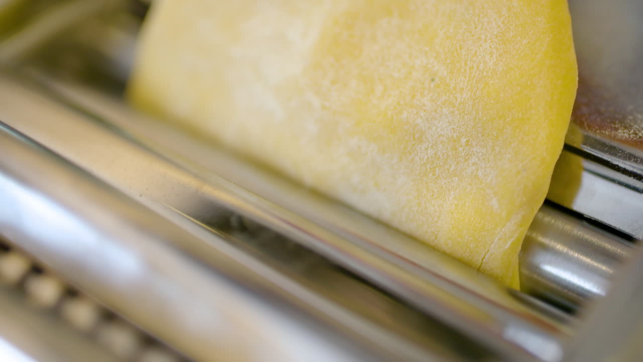 Close-up Tangan Meratakan Adonan Pasta Segar di Mesin Pasta