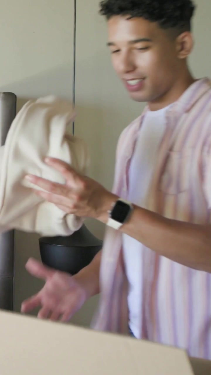 Vertical video: Opening box man in pink shirt lifting linen, walking to bedroom and preparing bed