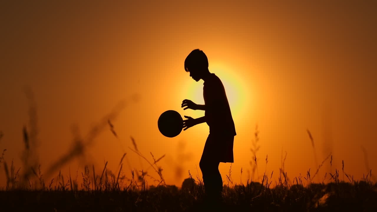 silueta de un niño jugando al fútbol o al fútbol en la playa con un hermoso trasfondo de puesta de sol infancia serenidad deporte concepto de estilo de vida.