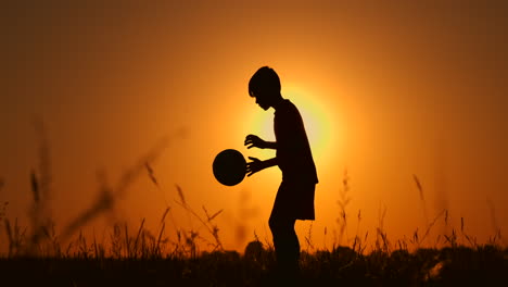 silhouette of a boy playing football or soccer at the beach with beautiful sunset background childhood serenity sport lifestyle concept.