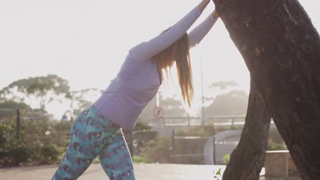 mujer caucásica estirándose en un parque