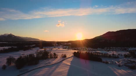 drone shot of mountains, fields, and landscape in winter at golden hour, sunrise with snow, flying over hills and fields with vibrant colors