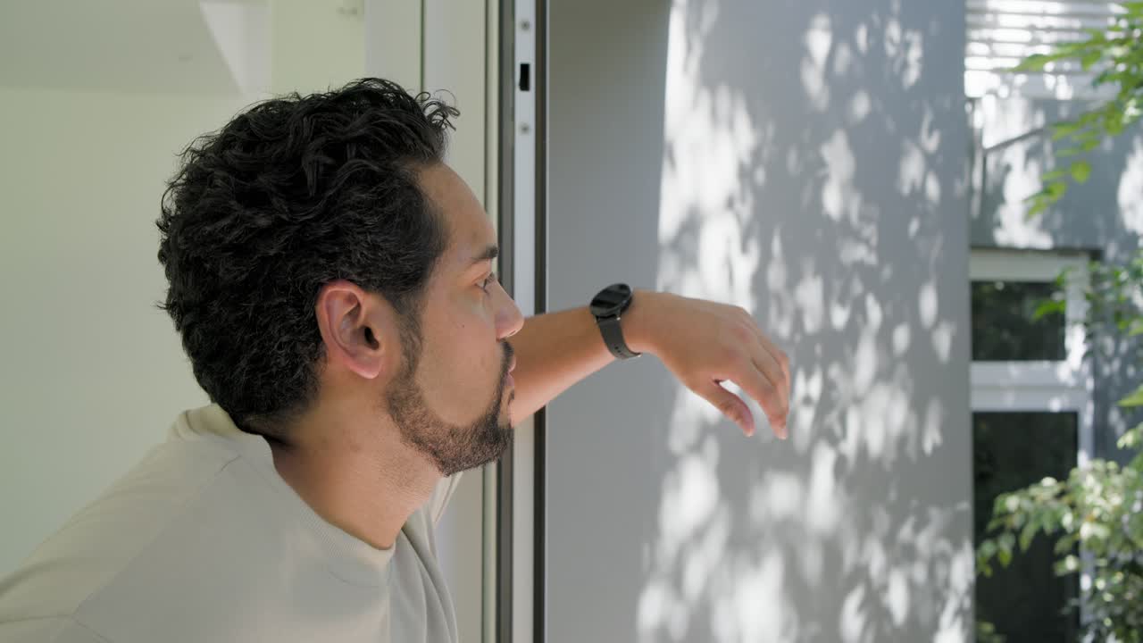 African American man leaning on frame, scanning wall with watch, smiling at camera, copy space