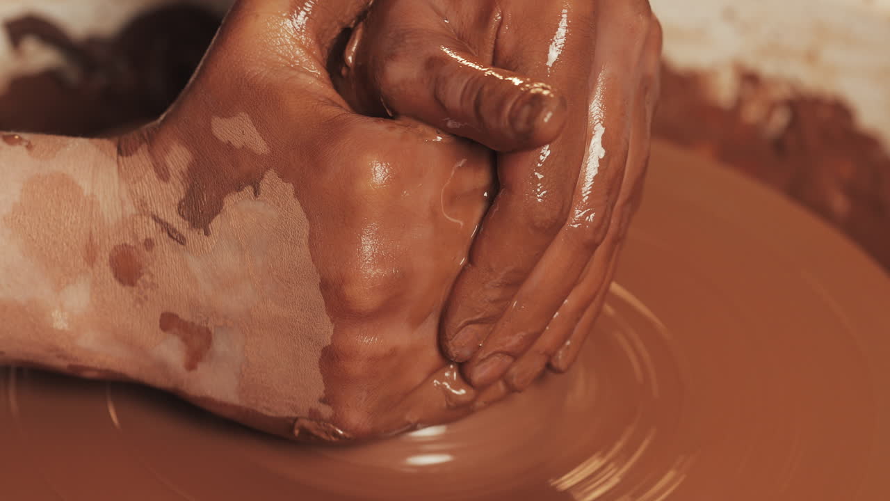 manos moldeando arcilla en una rueda de cerámica