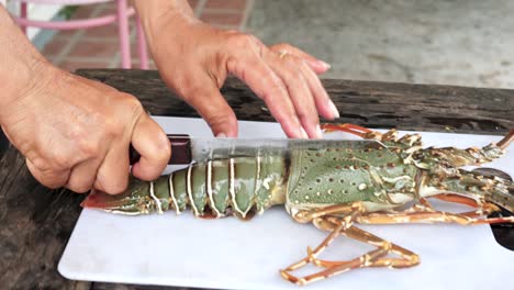 primer plano chef con cuchillo cortado langosta viva por la mitad, cocina al aire libre