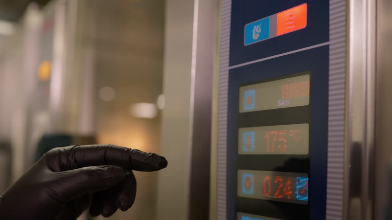 primer plano de una persona que programa la temperatura y el tiempo de un gran horno industrial tecnológico para cocinar varios platos al mismo tiempo