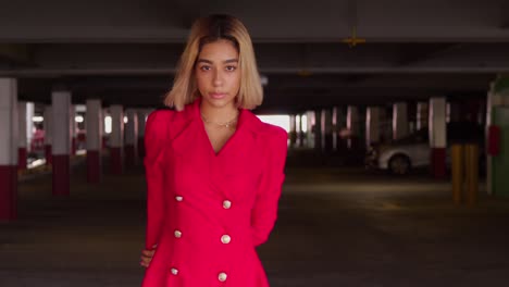 within the city's parking garage, a young hispanic girl walks in a short red dress