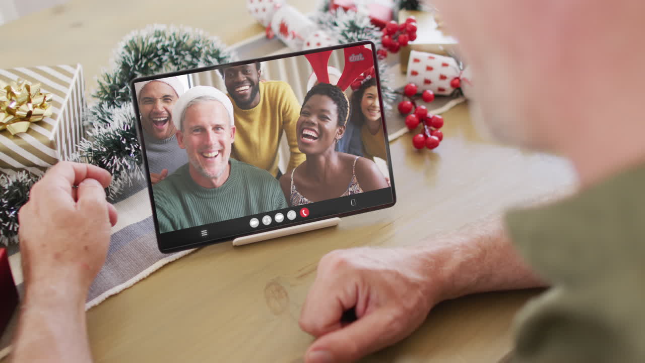 hombre caucásico con decoraciones de navidad teniendo llamada de video de tableta con diversos amigos