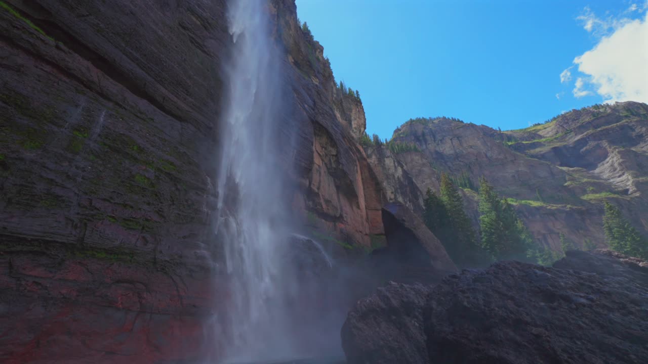 Mist spray Telluride Bridal Veil Falls Waterfall Black Bear Pass Road Colorado landscape pan down slow motion Ouray Ridgway Box Canyon cliffside hydropower house 4wd hiking blue sky creek windy