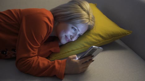 happy young woman texting on the phone while lying down.