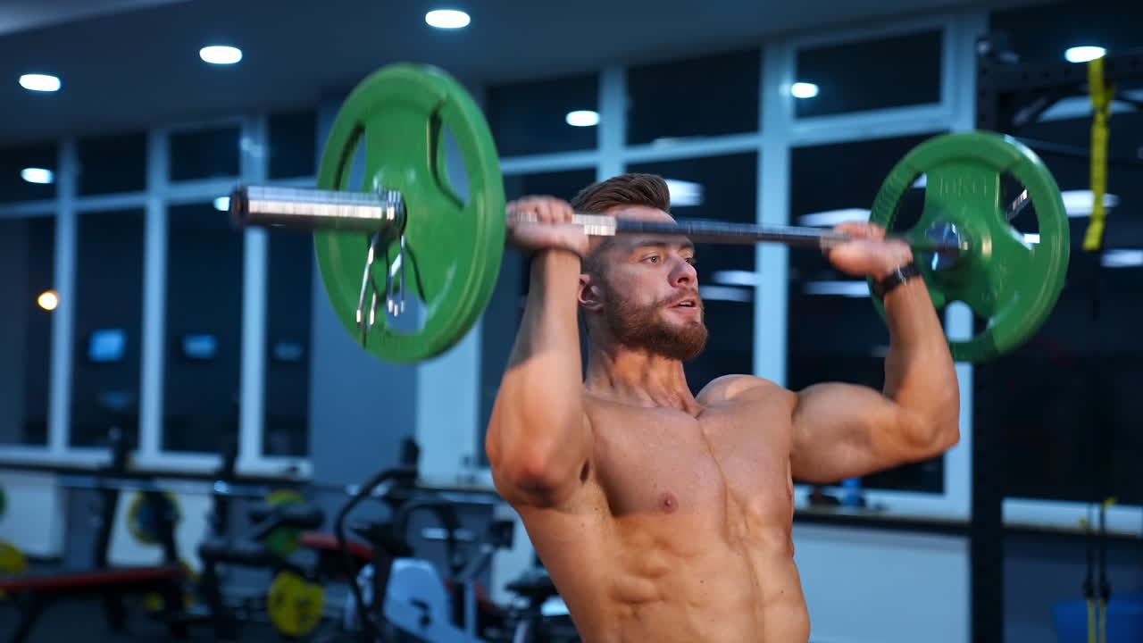 Bodybuilder doing weightlifting at gym. Muscular man working out in gym doing exercises with barbell