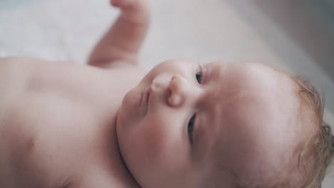 nice little newborn boy with tiny lips lies in baby bed