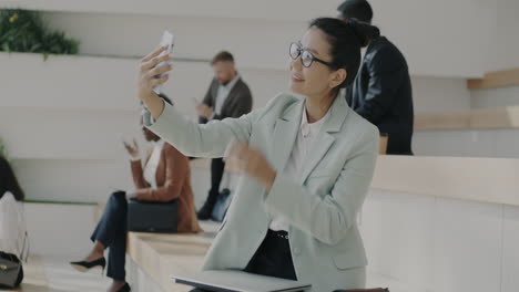 businesswoman taking selfie in office waiting area