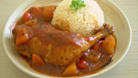 homemade chicken stew with tomatoes, onions, carrot and potatoes on plate with rice