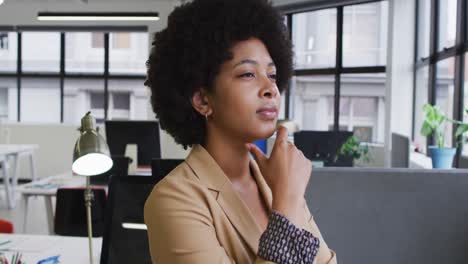 Mixed-race-businesswoman-rubbing-her-chin-in-thought-in-modern-office