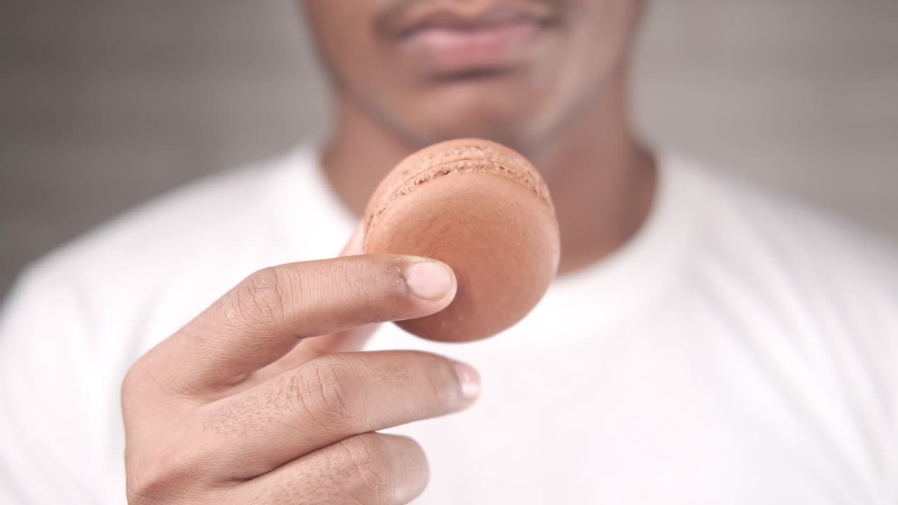 persona que sostiene un macarrón de chocolate