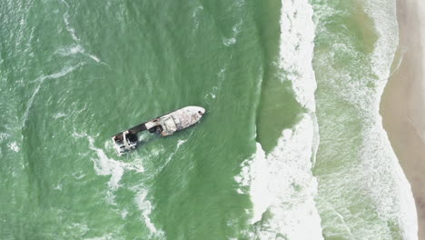 Boat-Submerged-In-Water-At-A-Beach-In-Namibia-South-Africa---aerial-shot