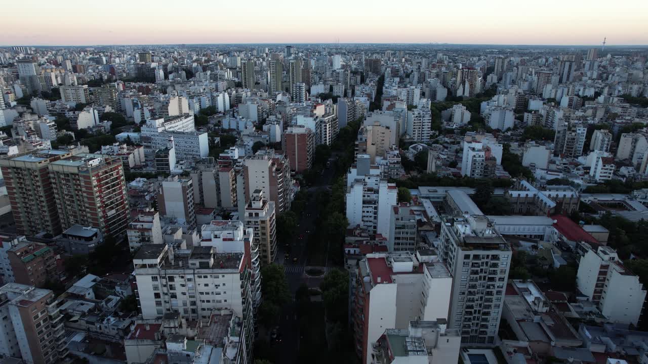 drone flying over a beautiful street with lots of trees in the middle of several buildings in buenos aires, argentina