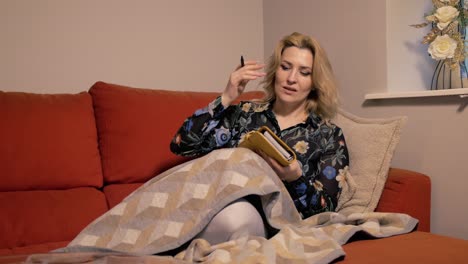 mujer saltando en el sofá emocionada escribiendo en el diario
